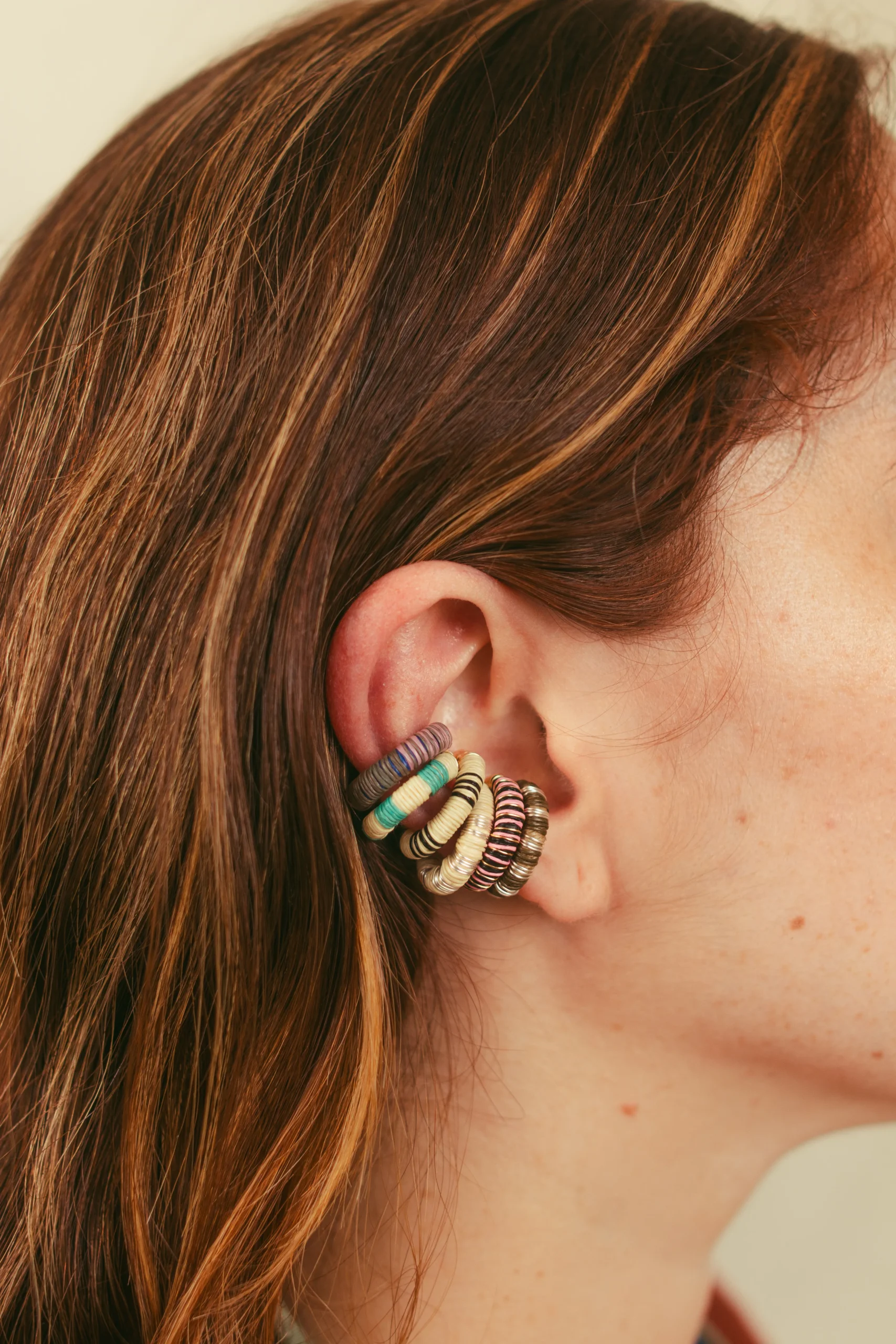 Detalle de oído con aretes artesanales apilados en plata, dorado y turquesa – Areito Gallery